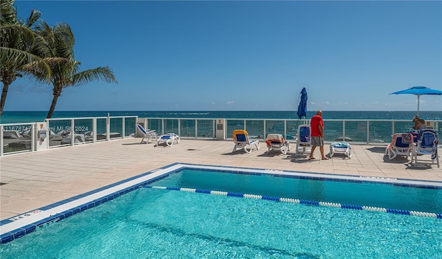 view of swimming pool with a water view and a patio area