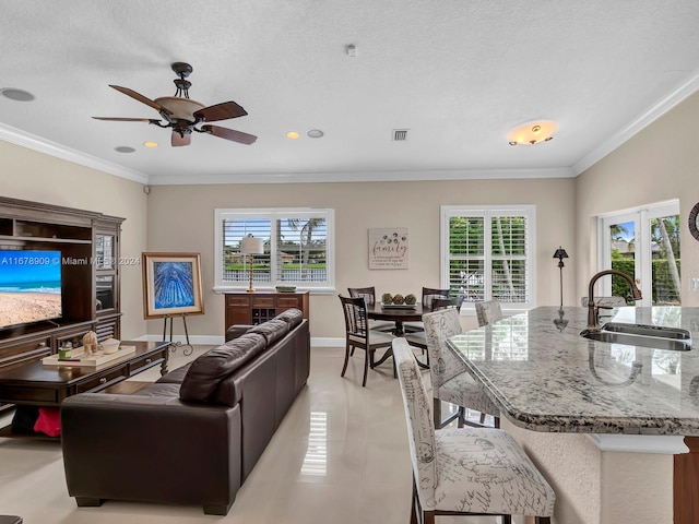 tiled living room featuring ornamental molding, a textured ceiling, sink, and plenty of natural light