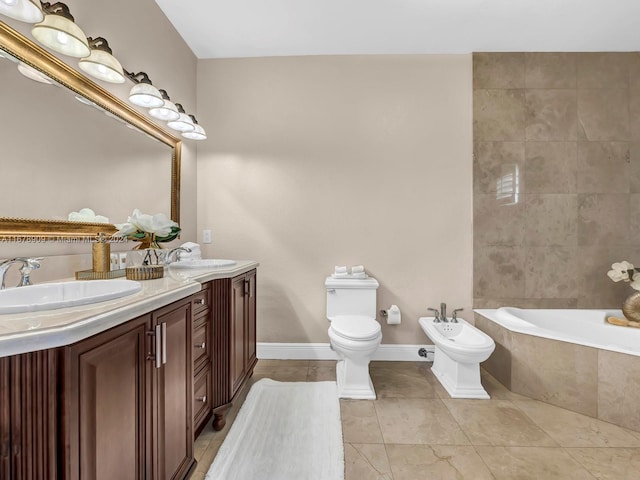 bathroom with vanity, a relaxing tiled tub, toilet, and a bidet