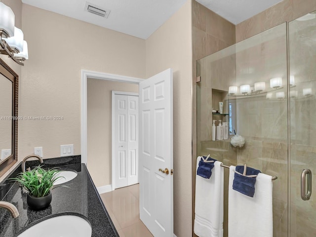 bathroom featuring a shower with door, vanity, and tile patterned floors