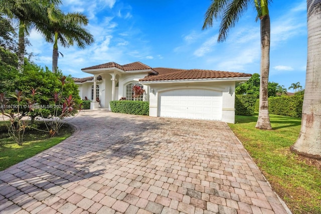 mediterranean / spanish-style house featuring a front yard and a garage