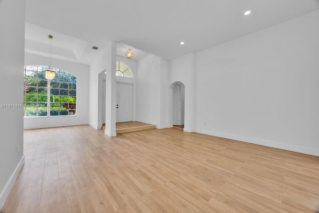 unfurnished living room featuring a chandelier and light hardwood / wood-style floors