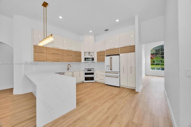 kitchen with appliances with stainless steel finishes, sink, white cabinetry, light hardwood / wood-style floors, and pendant lighting