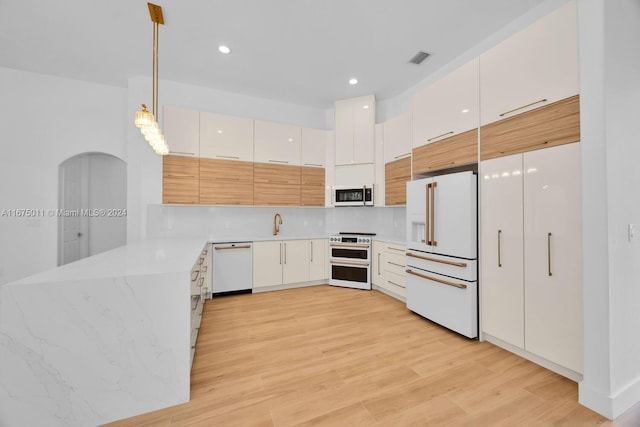 kitchen featuring white cabinets, tasteful backsplash, light hardwood / wood-style floors, decorative light fixtures, and white appliances