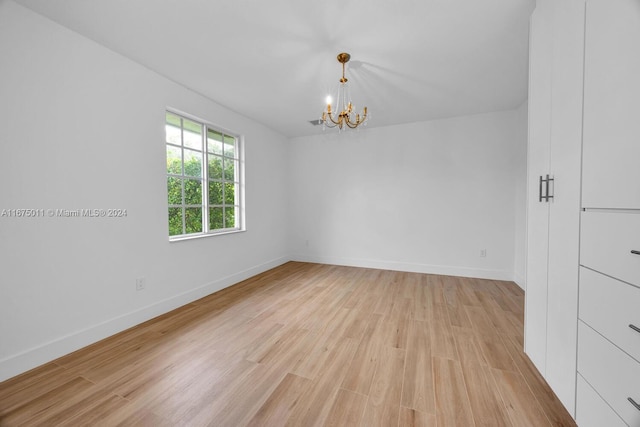 empty room with light hardwood / wood-style flooring and an inviting chandelier