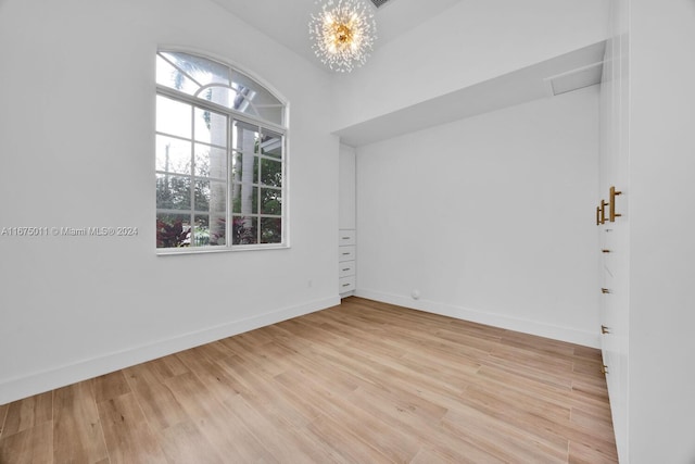 empty room featuring an inviting chandelier and light wood-type flooring