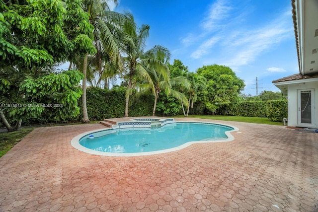 view of swimming pool featuring a patio area and an in ground hot tub