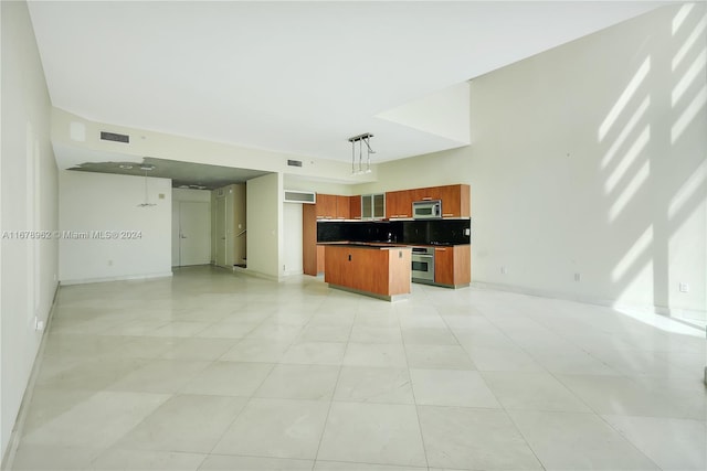 kitchen featuring tasteful backsplash, light tile patterned flooring, stainless steel appliances, and hanging light fixtures