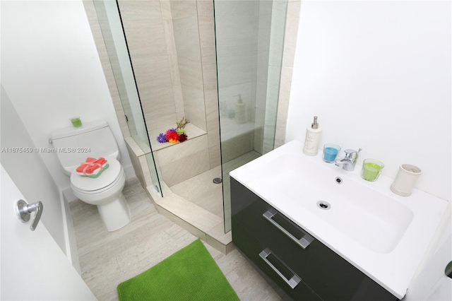 bathroom with vanity, tiled shower, hardwood / wood-style flooring, and toilet