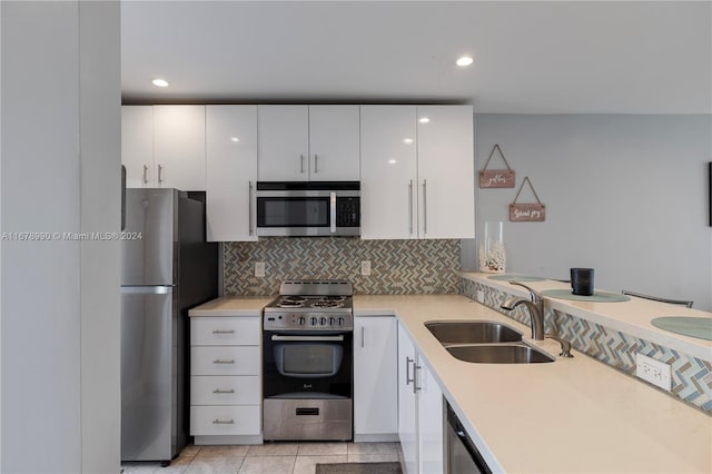 kitchen featuring appliances with stainless steel finishes, light tile patterned flooring, sink, backsplash, and white cabinetry