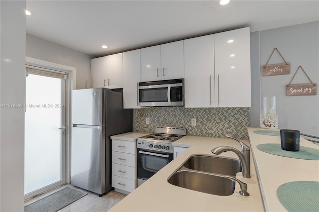 kitchen with tasteful backsplash, sink, light tile patterned flooring, white cabinetry, and stainless steel appliances