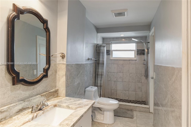 bathroom with a shower with shower curtain, toilet, tile walls, vanity, and tile patterned flooring