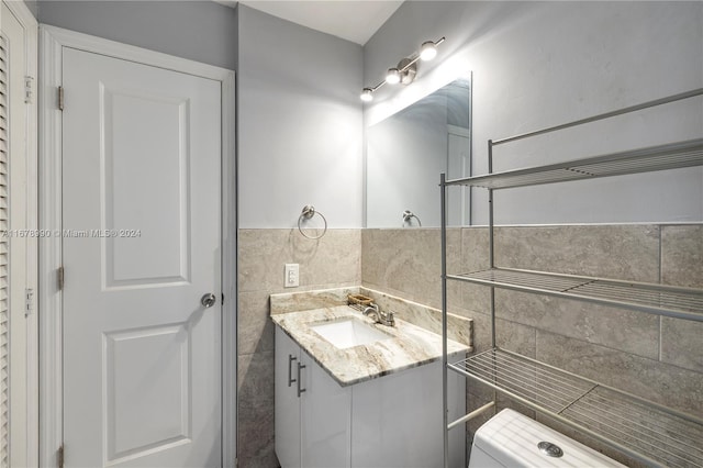 bathroom featuring vanity, toilet, and tile walls