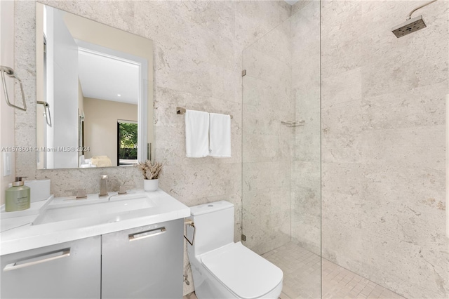 bathroom featuring tile patterned floors, tiled shower, toilet, vanity, and tile walls