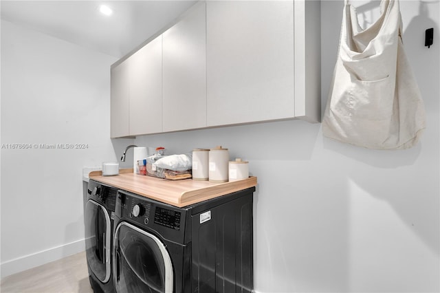 washroom featuring cabinets, light wood-type flooring, and washing machine and clothes dryer