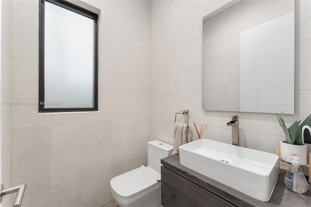 bathroom featuring vanity, tile walls, and toilet