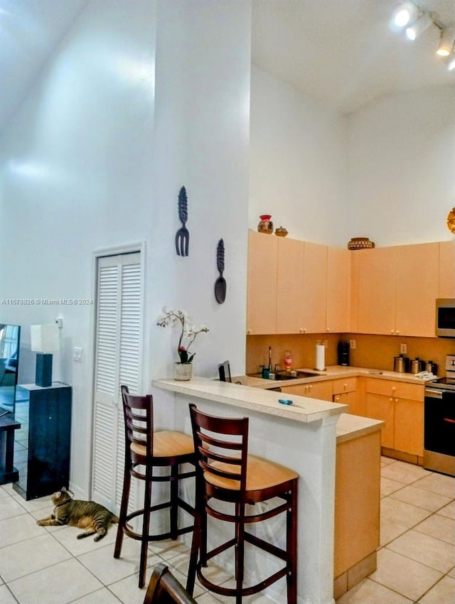 kitchen featuring electric stove, high vaulted ceiling, a breakfast bar, and kitchen peninsula