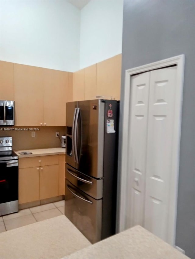 kitchen featuring stainless steel appliances, light tile patterned floors, and light brown cabinets