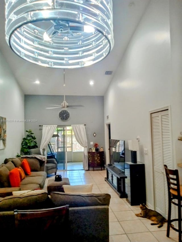 living room with ceiling fan, a high ceiling, and light tile patterned floors