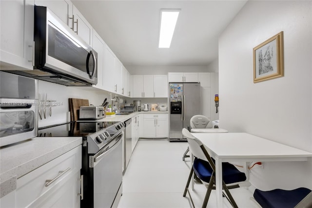 kitchen with appliances with stainless steel finishes, white cabinets, and light stone countertops