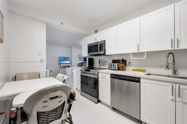 kitchen featuring appliances with stainless steel finishes, white cabinetry, sink, and light tile patterned floors