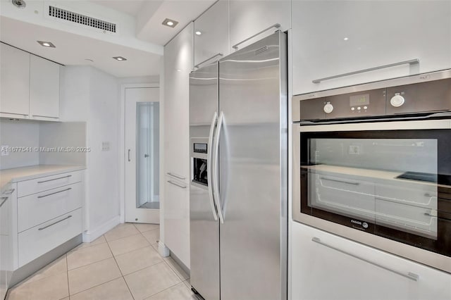 kitchen with light tile patterned flooring, white cabinetry, and stainless steel appliances