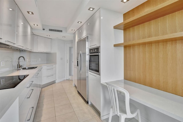 kitchen featuring sink, white cabinets, light tile patterned floors, and appliances with stainless steel finishes