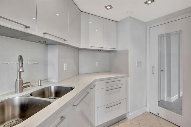 kitchen featuring light tile patterned flooring, white cabinetry, and sink