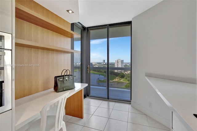 interior space with floor to ceiling windows, a water view, and light tile patterned flooring