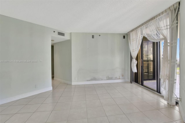 tiled empty room featuring a textured ceiling