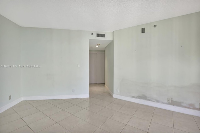 tiled empty room featuring a textured ceiling