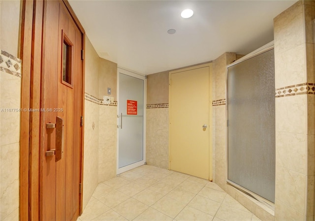 hall featuring light tile patterned floors and tile walls