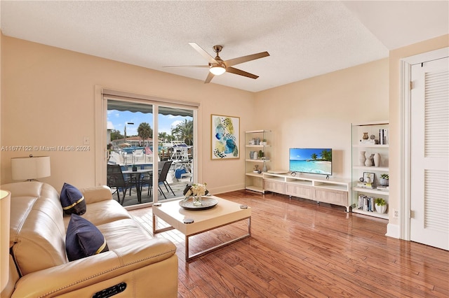 living room featuring hardwood / wood-style flooring, ceiling fan, and a textured ceiling