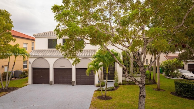 mediterranean / spanish-style home with a front lawn, central AC unit, and a garage