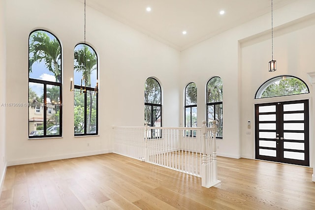 entrance foyer featuring a towering ceiling, light hardwood / wood-style flooring, and plenty of natural light