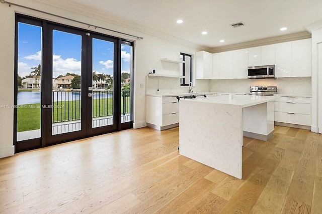 kitchen featuring french doors, stainless steel appliances, a center island, and white cabinets