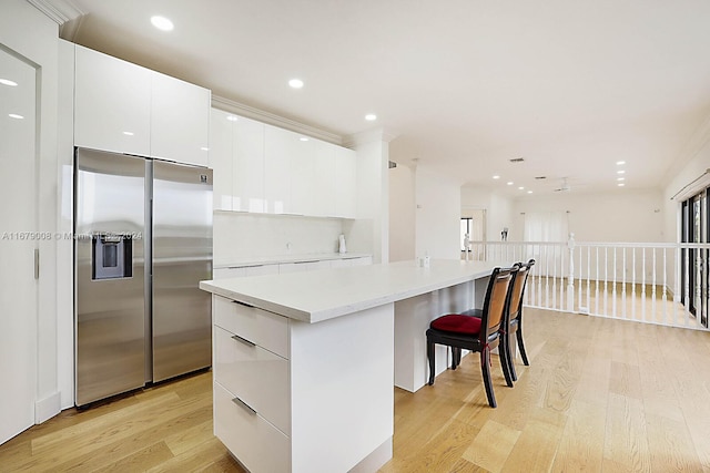 kitchen featuring stainless steel built in fridge, a center island, light hardwood / wood-style flooring, and white cabinetry