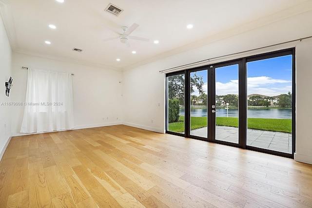 empty room featuring french doors, light hardwood / wood-style floors, ceiling fan, a water view, and crown molding