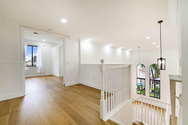 hall with ornamental molding and light hardwood / wood-style flooring