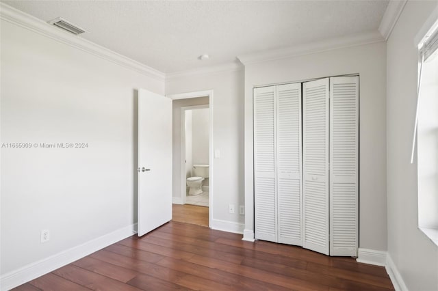 unfurnished bedroom featuring a closet, a textured ceiling, ornamental molding, and dark hardwood / wood-style flooring