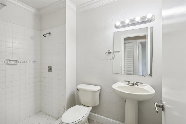 bathroom featuring tiled shower, crown molding, toilet, and sink