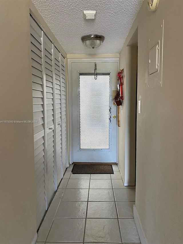 corridor featuring light tile patterned floors and a textured ceiling