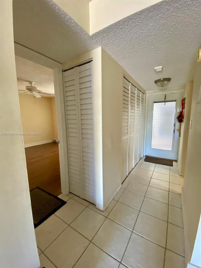 hallway featuring a textured ceiling and light tile patterned flooring