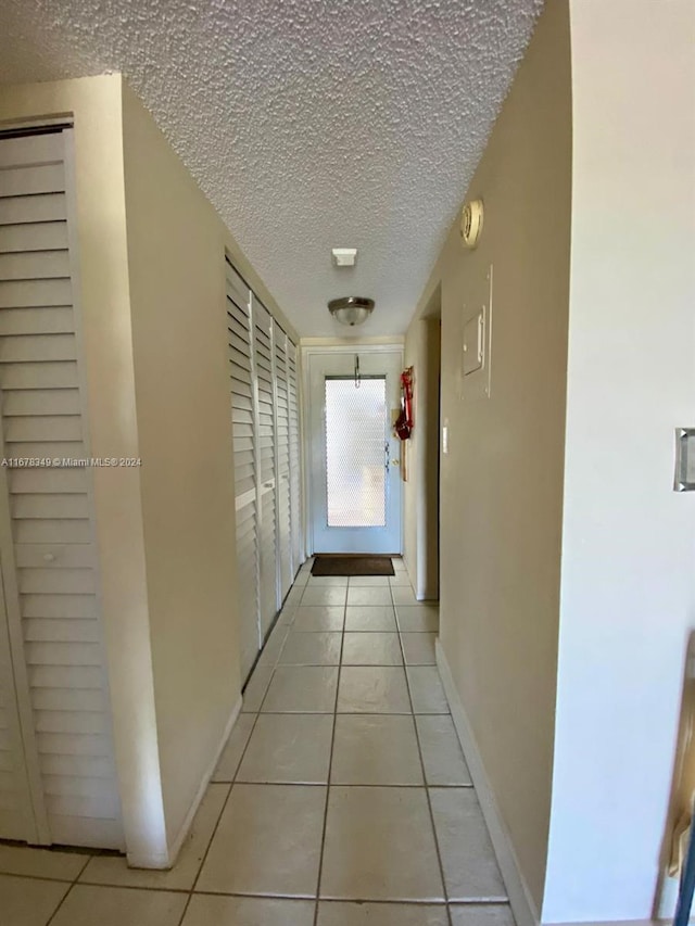 corridor with light tile patterned floors and a textured ceiling