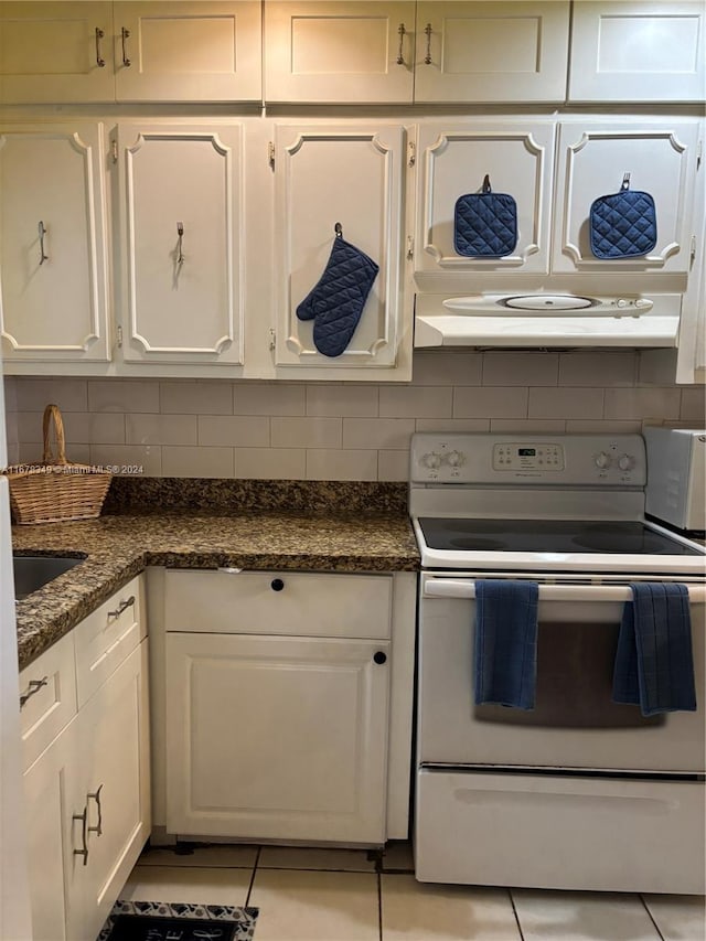 kitchen with white electric range oven, white cabinets, premium range hood, and light tile patterned flooring