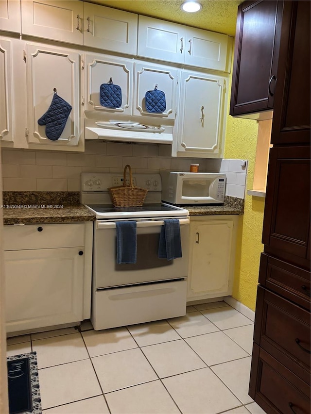 kitchen featuring tasteful backsplash, dark stone countertops, extractor fan, white appliances, and light tile patterned floors