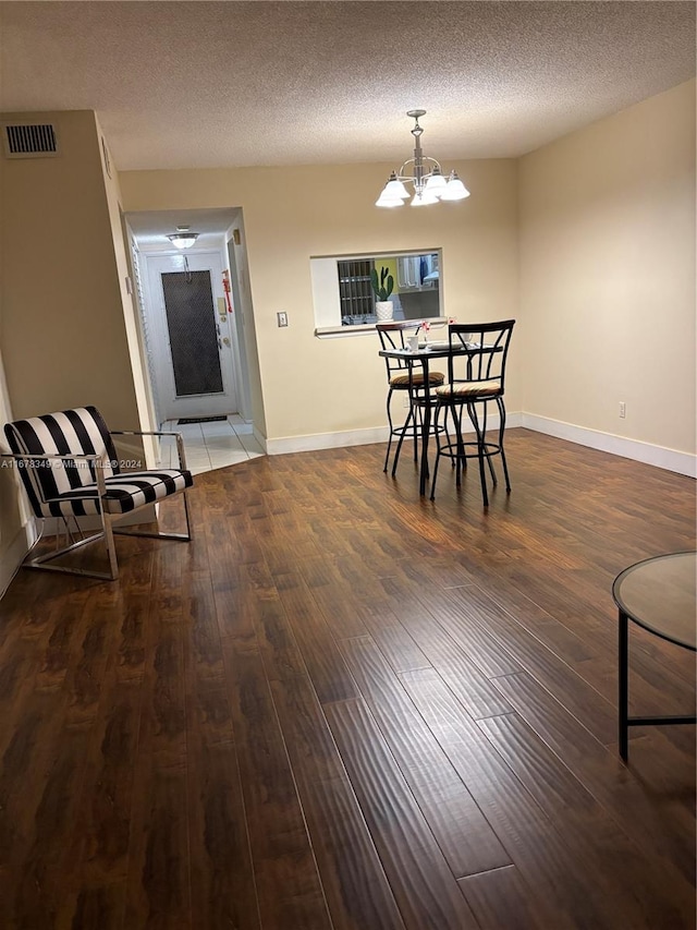 dining space featuring a textured ceiling, dark hardwood / wood-style flooring, and an inviting chandelier