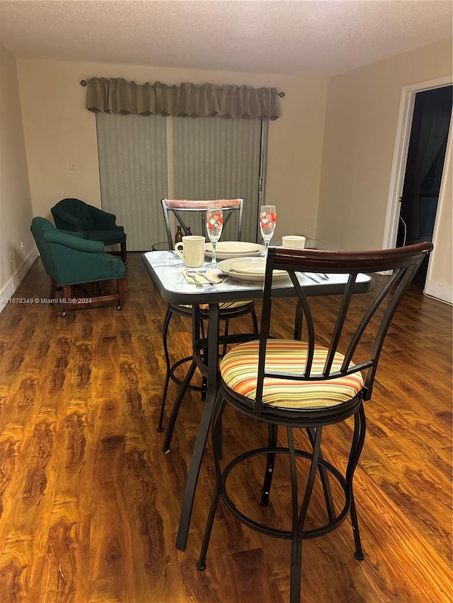 dining room with a textured ceiling and dark wood-type flooring