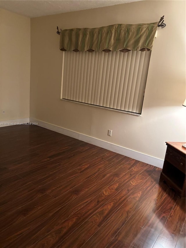 unfurnished room featuring dark hardwood / wood-style flooring and a textured ceiling