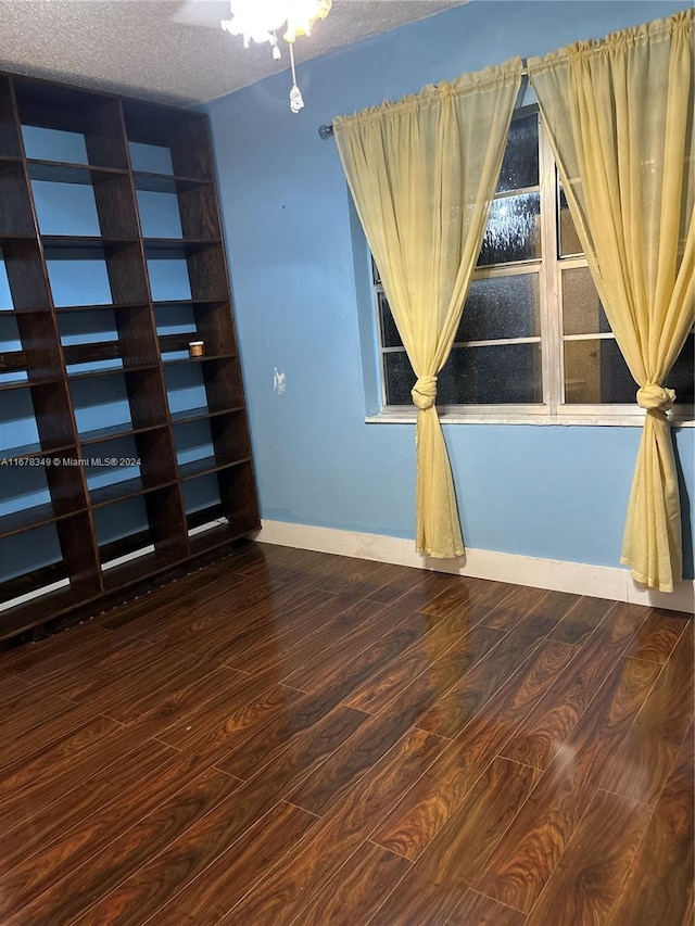 unfurnished room featuring wood-type flooring and a textured ceiling